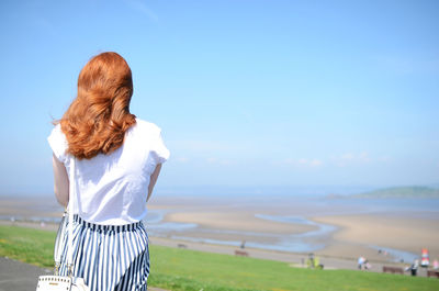 Rear view of woman standing on field against clear sky