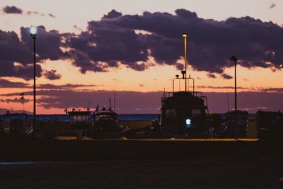 Silhouette sailboats on street against sky during sunset