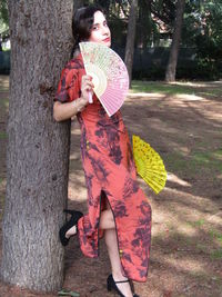 Full length of woman standing by tree trunk
