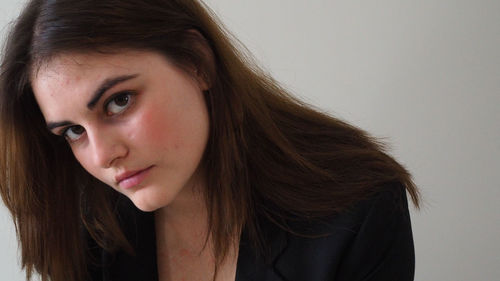 Close-up portrait of young woman against wall