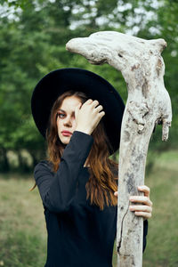 Portrait of young woman standing against trees