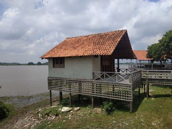 House by lake against sky