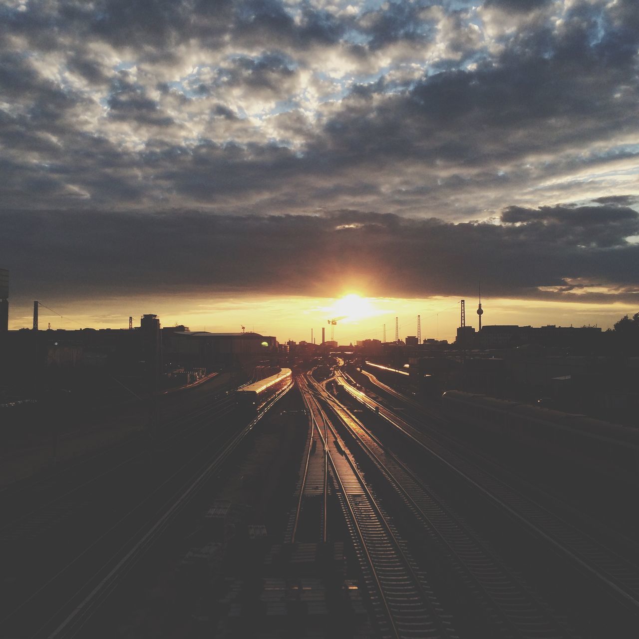 sunset, railroad track, sky, transportation, cloud - sky, rail transportation, the way forward, sun, vanishing point, cloudy, diminishing perspective, public transportation, orange color, silhouette, cloud, railroad station platform, railroad station, sunlight, nature, sunbeam