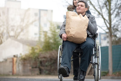 A woman pushes a physically disabled person in a wheelchair after shopping.