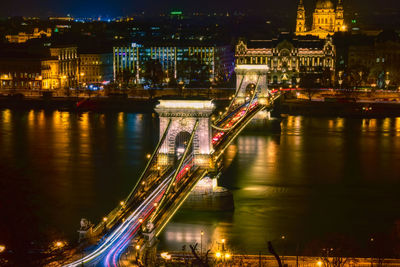 Illuminated bridge over river in city at night