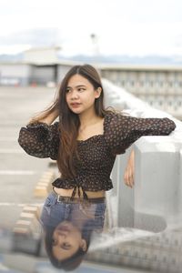 Portrait of young woman standing against sky