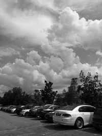 Vehicles on street against cloudy sky