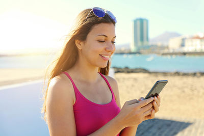 Young woman using mobile phone while standing at beach