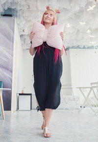 Portrait of young woman standing against wall