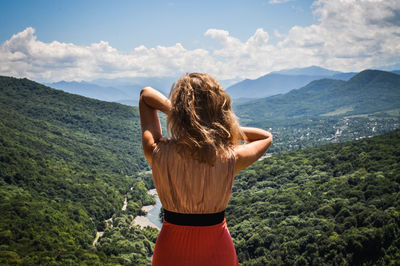 Rear view of woman standing on mountain against sky