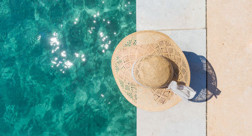 Directly above shot of woman wearing hat sitting by sea