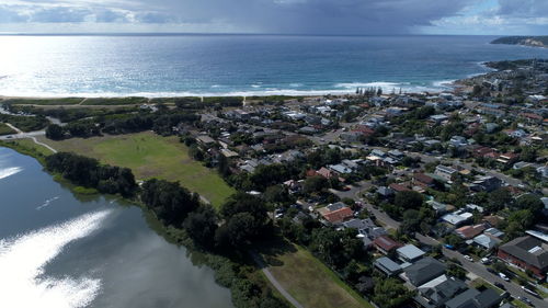 Aerial view of townscape by sea against sky