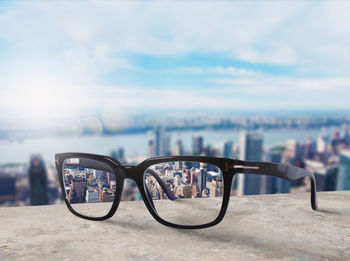 Close-up of eyeglasses on street against sky