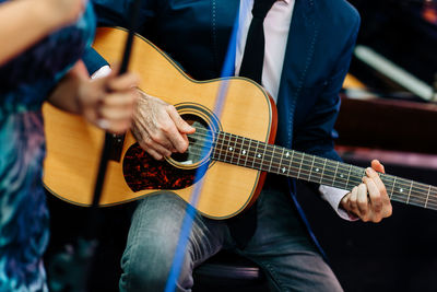 Midsection of man playing guitar while sitting outdoors