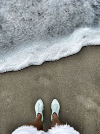 The girl is standing on the shore of the ocean.