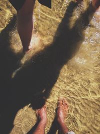 Low section of woman standing on sand at beach