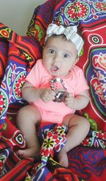 Portrait of cute baby girl relaxing on bed at home