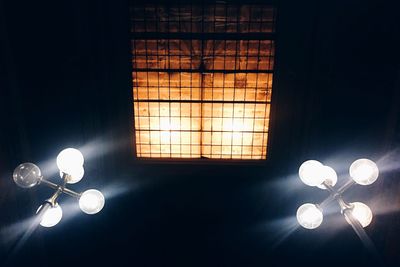 Low angle view of illuminated light bulb against black background