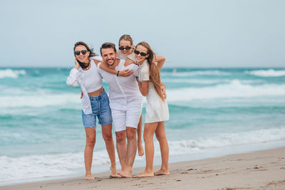 Portrait of smiling friends standing at beach