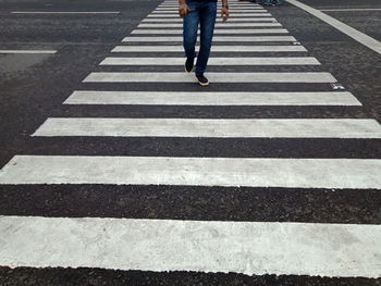 Low section of person walking on zebra crossing