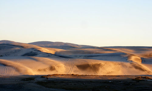 Scenic view of desert against clear sky on sunny day