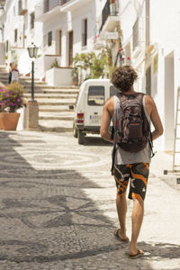 Rear view of man walking on street by buildings