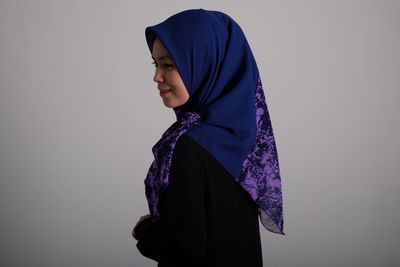 Side view of young woman wearing hijab while standing against wall