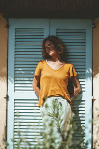 Thoughtful mature woman standing in front of blue door