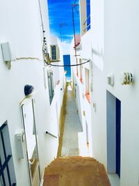 Empty road amidst buildings against white wall