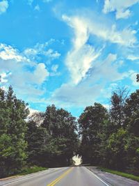 Empty road amidst trees against sky