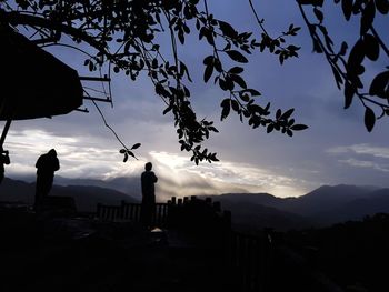 Silhouette man by tree against sky during sunset