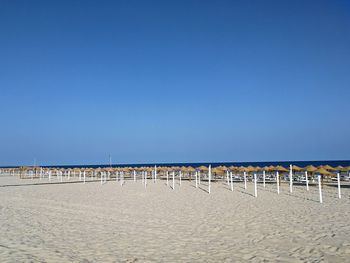 Rows of parasols on manta rota beach against clear blue sky