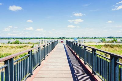 Footbridge leading to bridge against sky