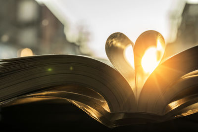 Close-up of heart shape made with pages on open book against sky