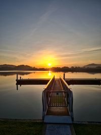 Pier over lake against sky during sunset