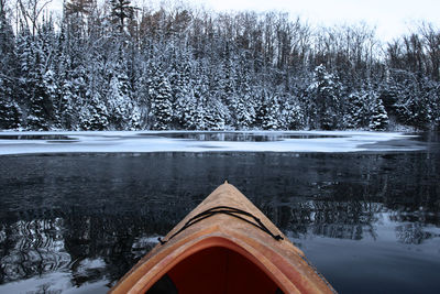 Boat in lake against bare trees during winter