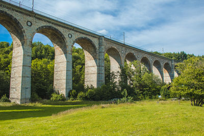 Arch bridge on landscape against sky