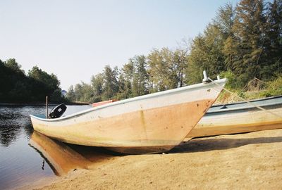 Boat on lake by trees against sky