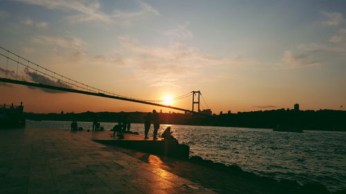 Bridge over sea against sky during sunset