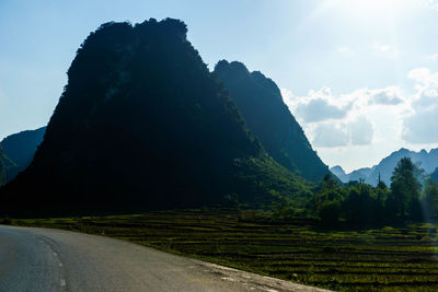 Scenic view of road by mountains against sky