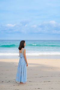 Full length of woman standing on beach against sea