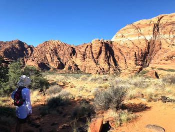 Rear view of woman standing against rock formation