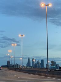 Illuminated street lights against sky at dusk