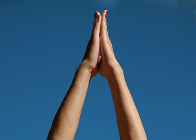 Low section of human feet against clear blue sky