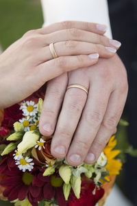 Hands of bride and groom with flower bouquet and wedding rings