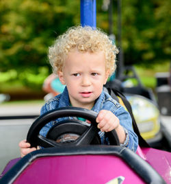 Close-up of cute boy riding toy car