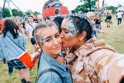 Portrait of smiling young woman being kissed by friend at party