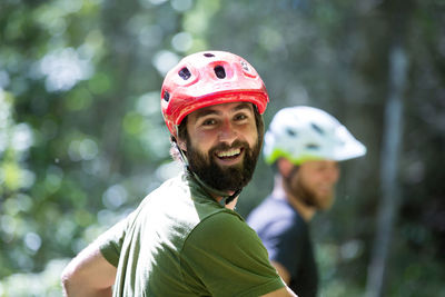 Portrait of happy hiker in cycling helmet with friend in background