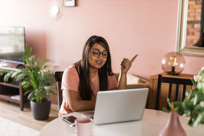 Young woman using mobile phone while sitting on table