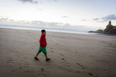 Full length of boy on beach against sky